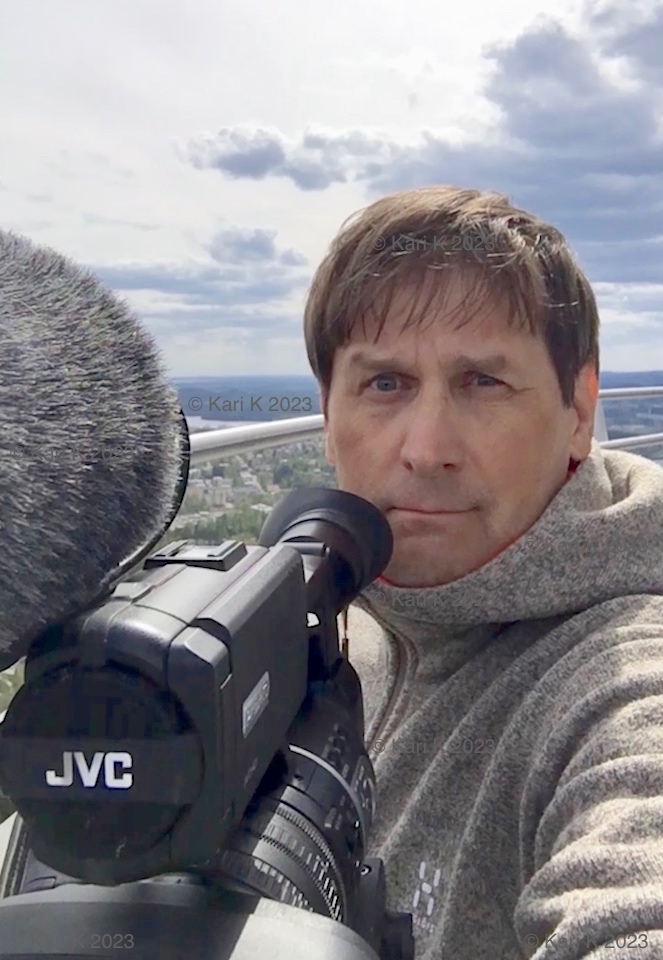 Valokuvassa henkilö Kuopiossa Puijon tornin näköalatasanteella kuvaamassa videokameralla.